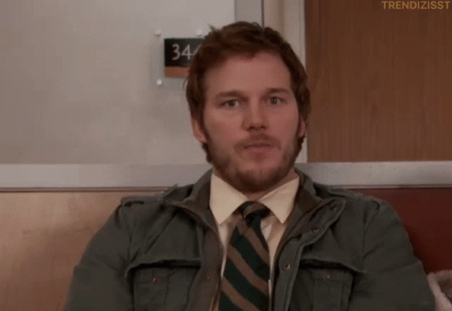 Man In Jacket And Tie Sitting By 34 Sign GIF