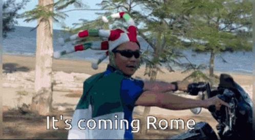 Man in Jester Hat and Sunglasses Saying It's Coming Rome on Beach