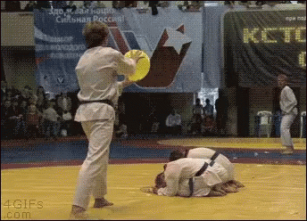 Man In Karate Uniform Holding Yellow Frisbee With ICT Sign GIF