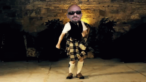 Man In Kilt Dancing In Front Of Brick Wall GIF