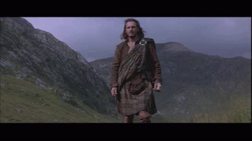 Man in Kilt in Field with Mountains