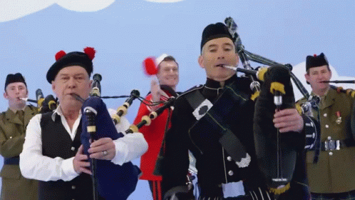Man in Kilt Playing Bagpipe for Group of Men