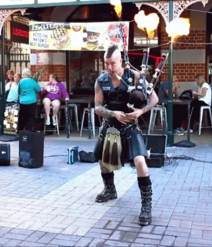 Man in Kilt Playing Bagpipes with Biscuits Sign