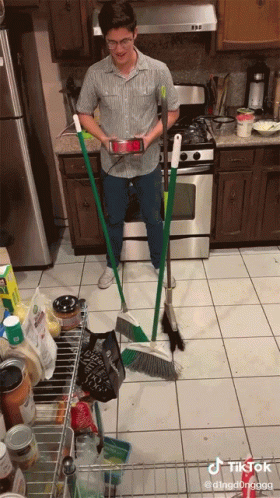 Man in Kitchen Holding Broom and Phone