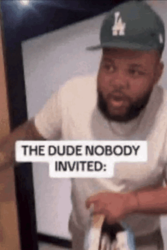 Man in LA Hat Standing in Doorway With Sign The Dude Nobody Invited