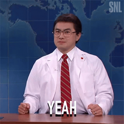 Man in Lab Coat and Tie Sitting at Desk Saying Yeah