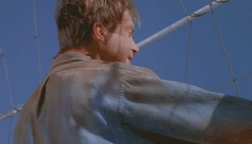Man In Leather Jacket Against Blue Sky And Fence GIF