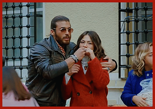Man in Leather Jacket Hugging Woman in Red Coat