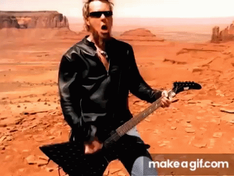 Man in Leather Jacket Playing Guitar in Desert