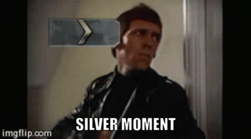 Man in Leather Jacket Standing in Front of Silver Moment Sign