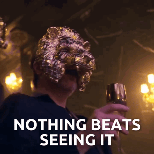 Man in Lion Mask Holding Glass Saying Nothing Beats Seeing It