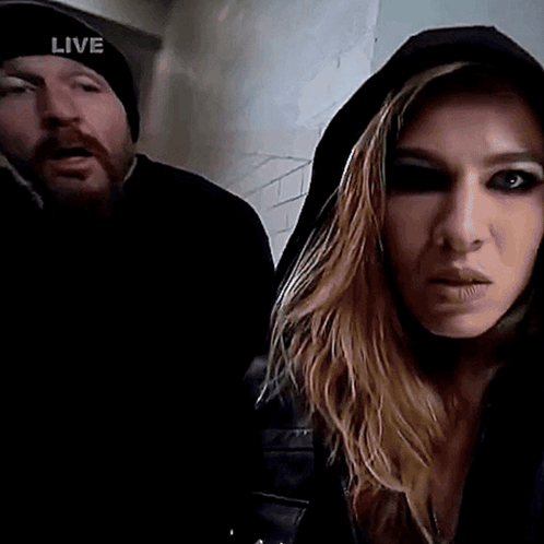 Man in Live Hat Next to Hooded Woman