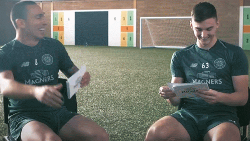 Man In Magners Shirt Sitting Next To Man In New Balance Shirt GIF