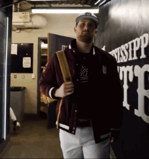 Man in Maroon Jacket and White Pants Walking Past Mississippi