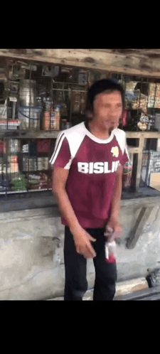 Man in Maroon Shirt Saying Bisli in Front of Store