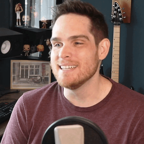 Man in Maroon Shirt Smiling at Microphone
