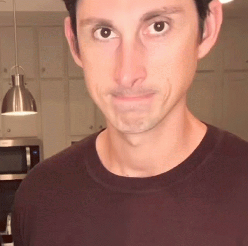 Man In Maroon T-Shirt Looks At Camera GIF