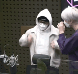 Man in Mask and Hoodie Standing Next to Another Man