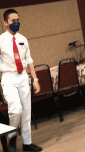 Man in Mask and Red Tie Standing at Table