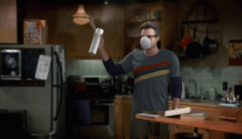 Man In Mask Holding Spray Bottle In Kitchen GIF