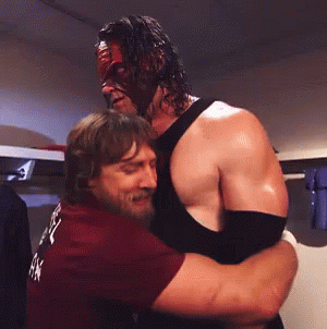 Man in Mask Hugging Man in Maroon Shirt