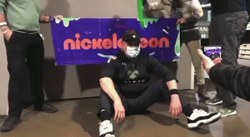 Man in Mask in Front of Nickelodeon Sign