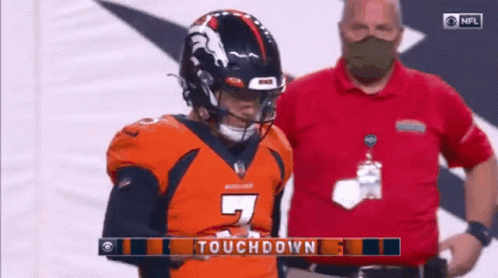 Man In Mask Standing Next To Football Player In Orange Jersey GIF