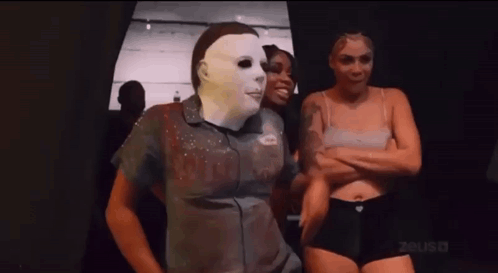 Man In Mask Standing Next To Two Women In Underwear GIF