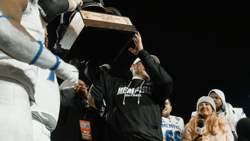 Man in Memphis Football Shirt Holding Trophy