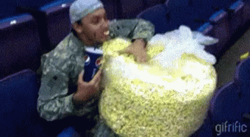 Man in Military Uniform Eating Large Bag of Popcorn