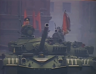 Man in Military Uniform on Tank Holding Gun