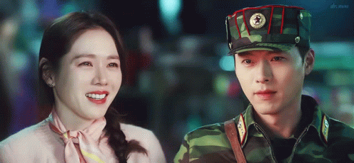 Man In Military Uniform Smiling Next To Woman In Pink GIF