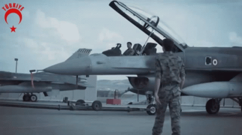 Man in Military Uniform Stands in Front of Fighter Jet With Word Turkey