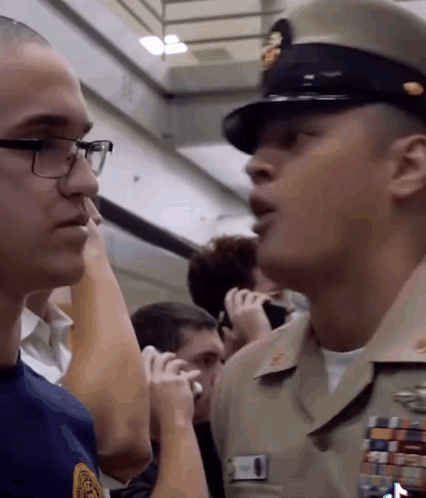 Man In Military Uniform Talking To Glasses Man GIF