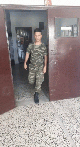 Man in Military Uniform Walking Out of Doorway