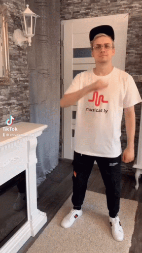 Man In Musical.ly T-Shirt Standing By Fireplace GIF