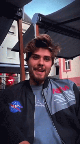 Man in NASA Jacket Sitting Under Umbrella