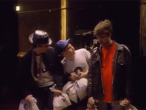 Man In NASA Shirt Talking To Two Men Holding Money Bags GIF
