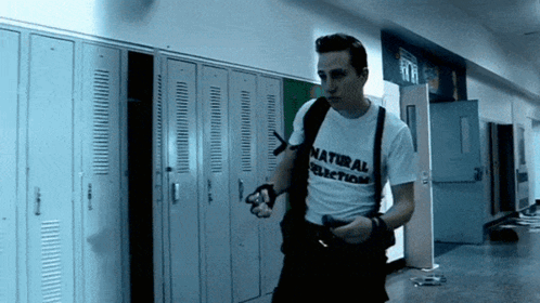 Man In Natural Selection Shirt Walking Down Hallway GIF