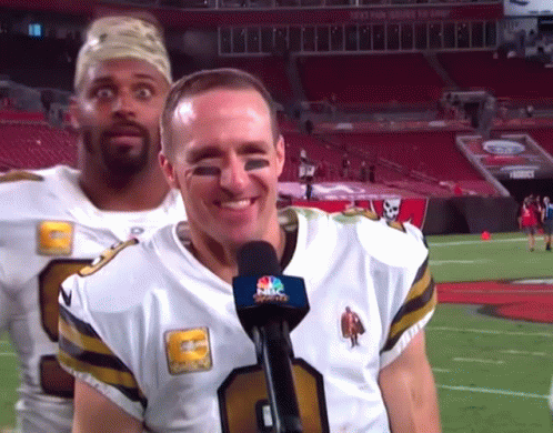 Man in NBC Sports Jersey Smiling Next to Another Man