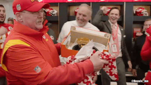 Man in NFL Hat Holding Box With Hamburger