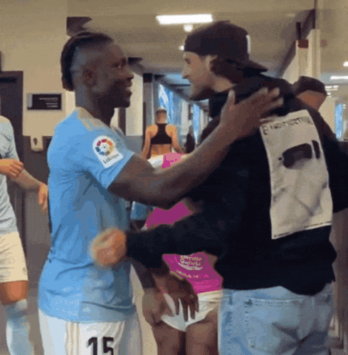 Man in Number 15 Jersey Hugging Man in Black Shirt