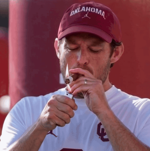 Man In Oklahoma Hat Lighting Cigar GIF