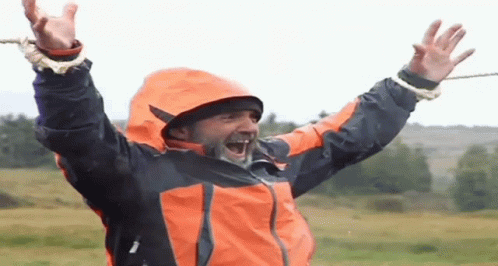 Man in Orange and Black Jacket Laughing Arms Up
