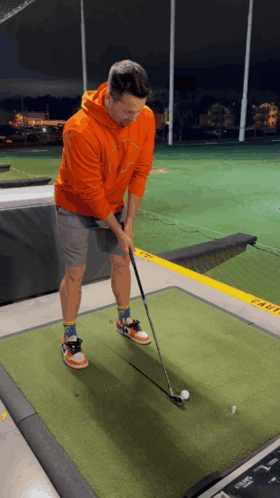 Man in Orange Hoodie Playing Golf