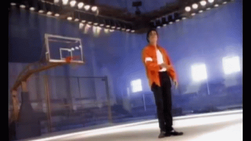 Man in Orange Jacket Standing in Front of Basketball Hoop