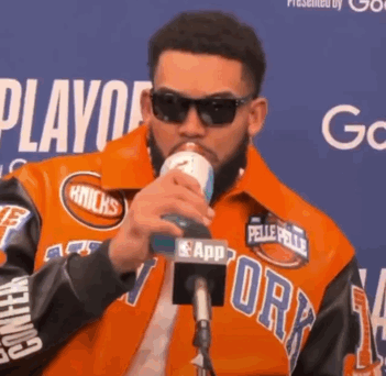 Man In Orange Knicks Jacket Drinking From Can GIF