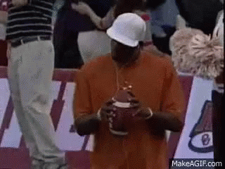 Man in Orange Shirt and White Hat Holding Football