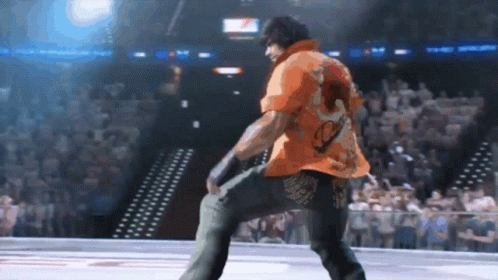 Man In Orange Shirt Dancing In Stadium GIF