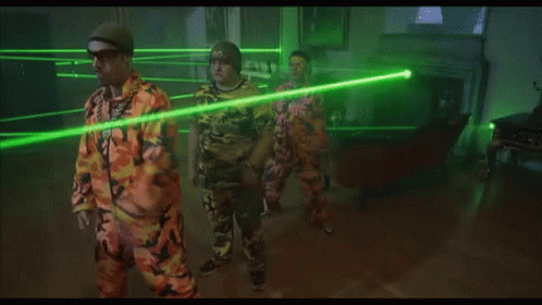 Man in Orange Shirt Facing Green Laser Beams